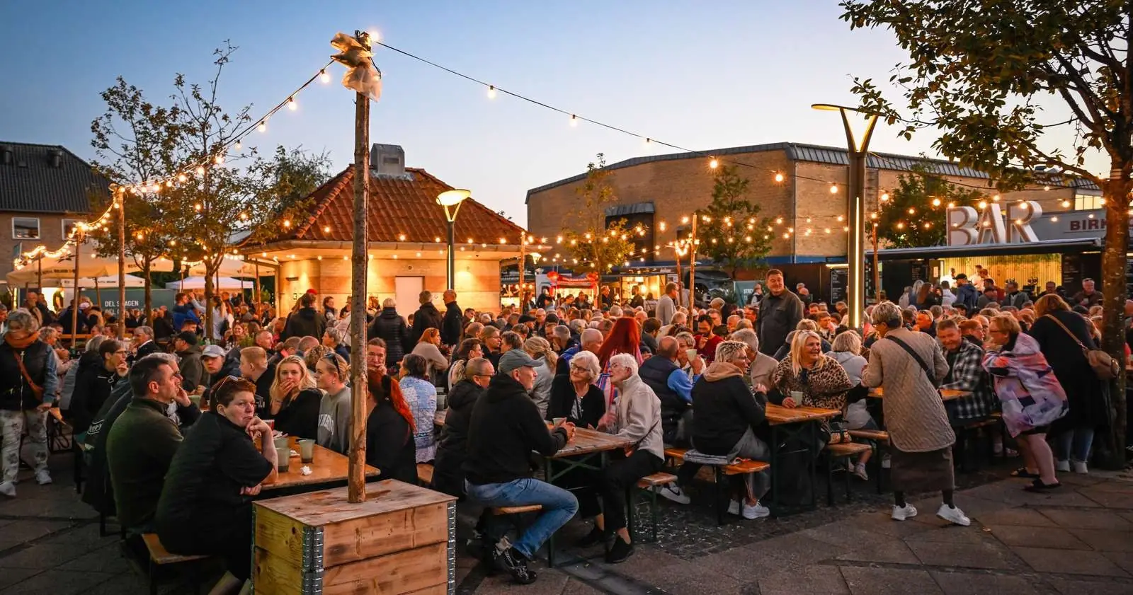 People gathered at long tables under string lights at Street Food in Grindsted